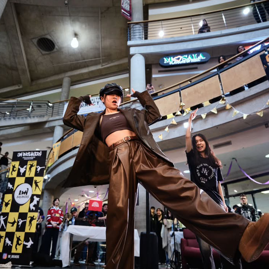 A dancer striking a freestyle pose in front of the UW Breakers banner at Ground FX
