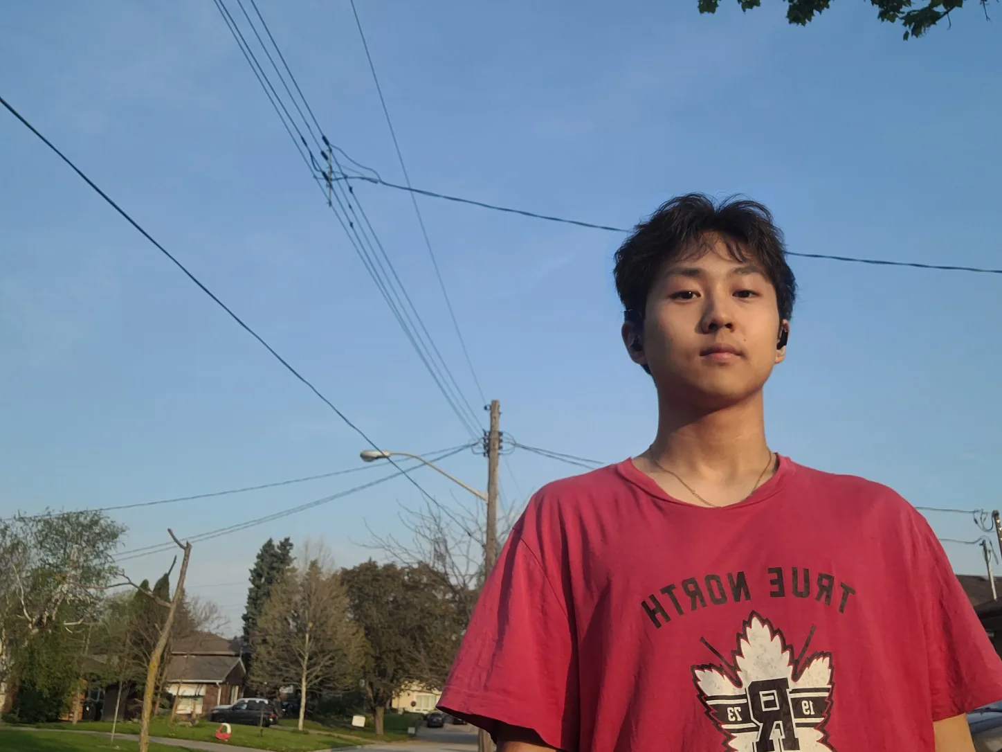 Jaydon standing on a residential street at golden hour, power lines crossing the sky behind him